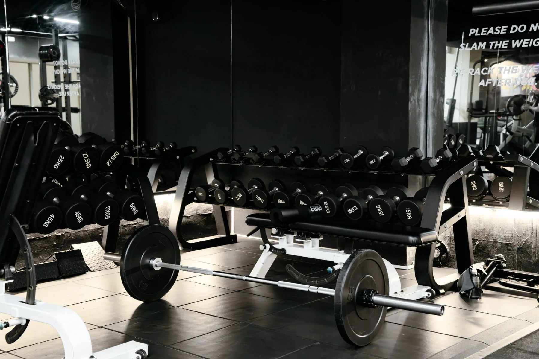 Unstoppable Fitness - A Modern gym with the latest weightlifting equipment, including dumbbells on racks and a bench, on a tiled floor.