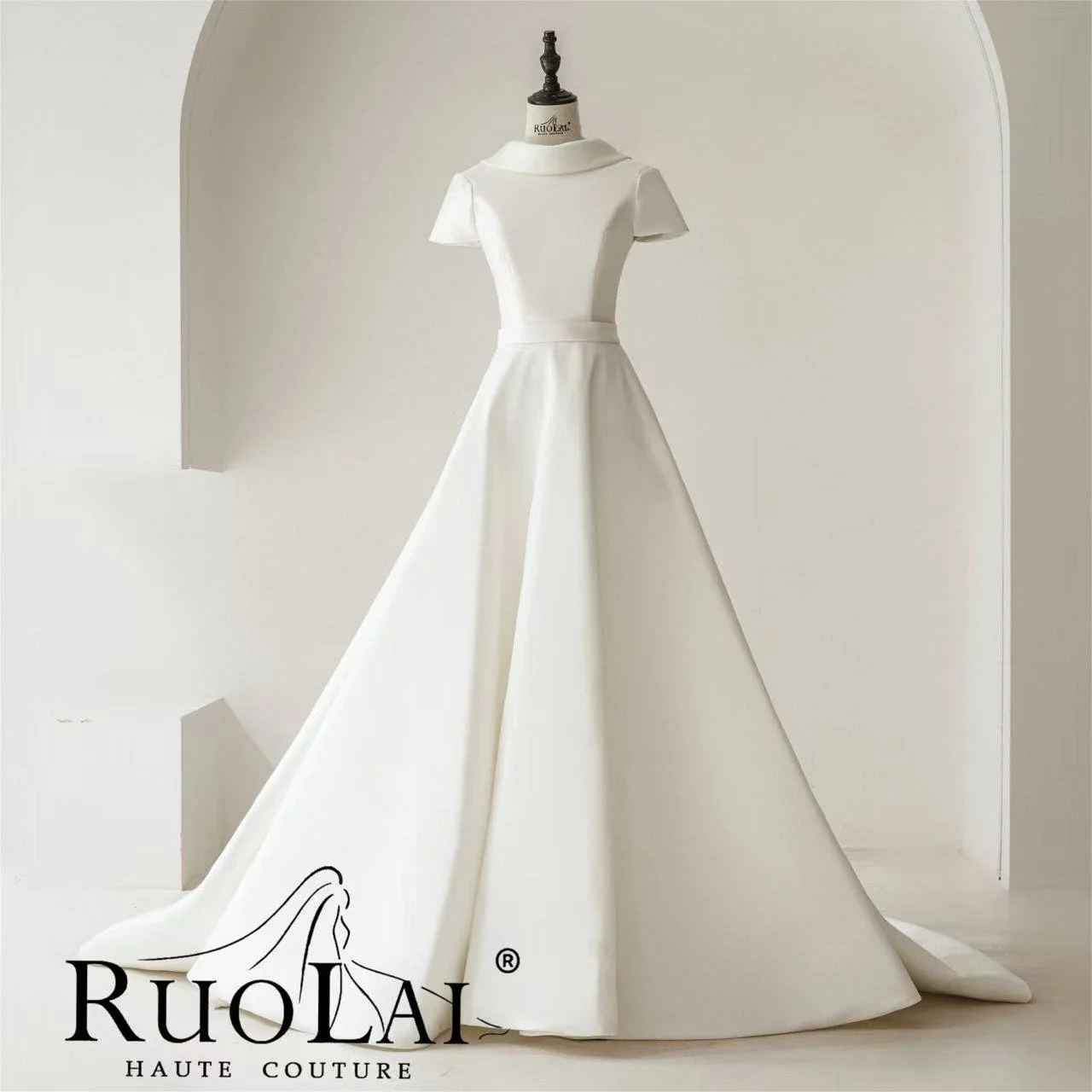 A white wedding gown on a mannequin with a fitted bodice, short sleeves, and a full A-line skirt with a long train, displayed against a white background with a logo that says Ruolai Haute Couture.