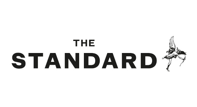 Logo for The Standard featuring black text and a small illustration of a winged dancer on the right.