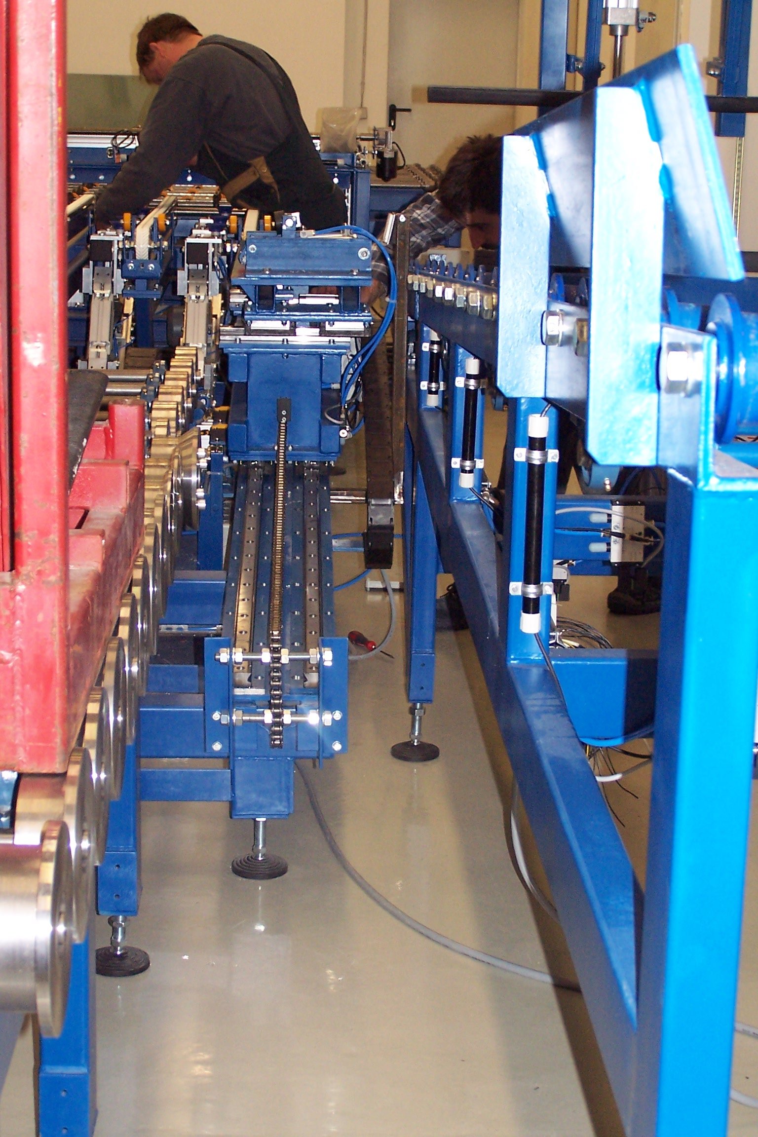Zwei Personen arbeiten an einer technischen Maschine in einer Fabrikhalle.