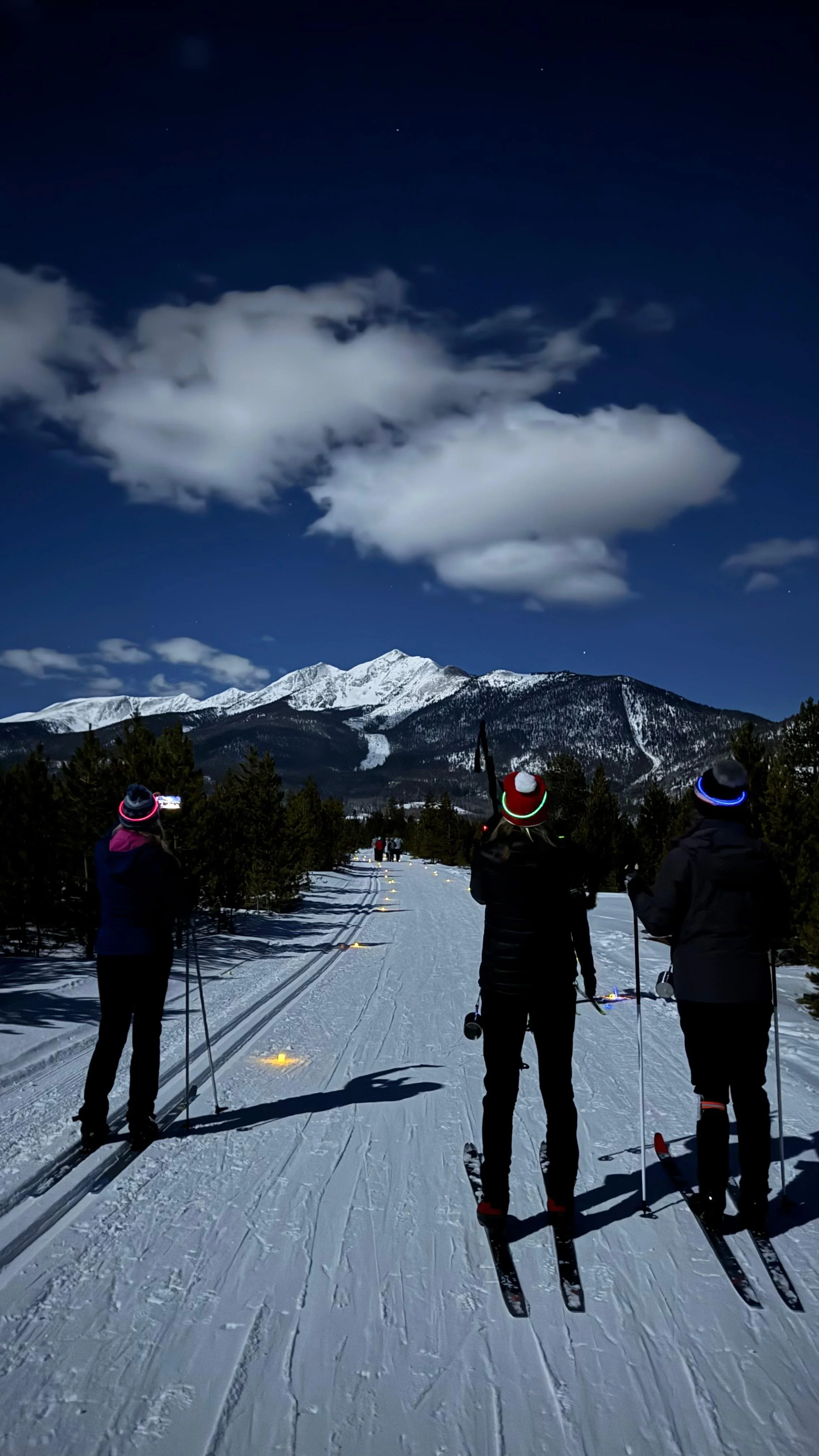 Spoke members cross-country skiing together on a snowy trail beneath the mountains in Summit County.