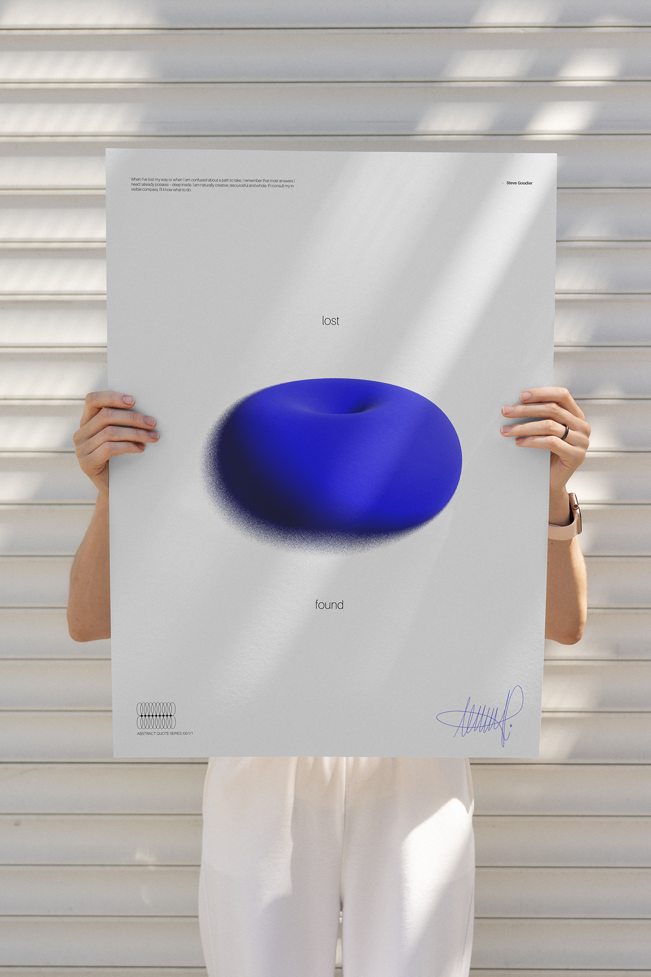 Person holding a large poster with a blue abstract shape and the words 'lost' and 'found',-standing in front of a white slatted wall, shadows cast across the poster.