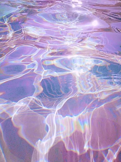 Close-up of water with light reflections creating colorful ripple patterns.
