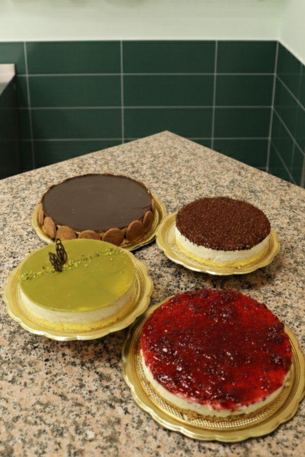 Quattro torte di diversi gusti disposte su un bancone in una cucina.