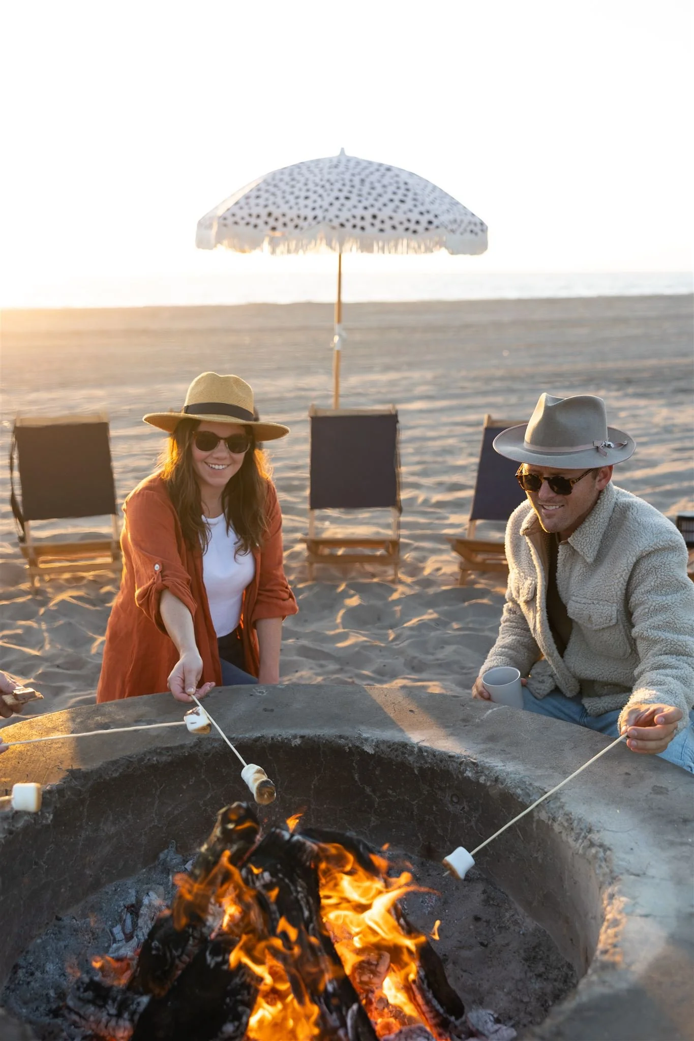 People roasting marshmallows and making smores over a bonfire at the beach