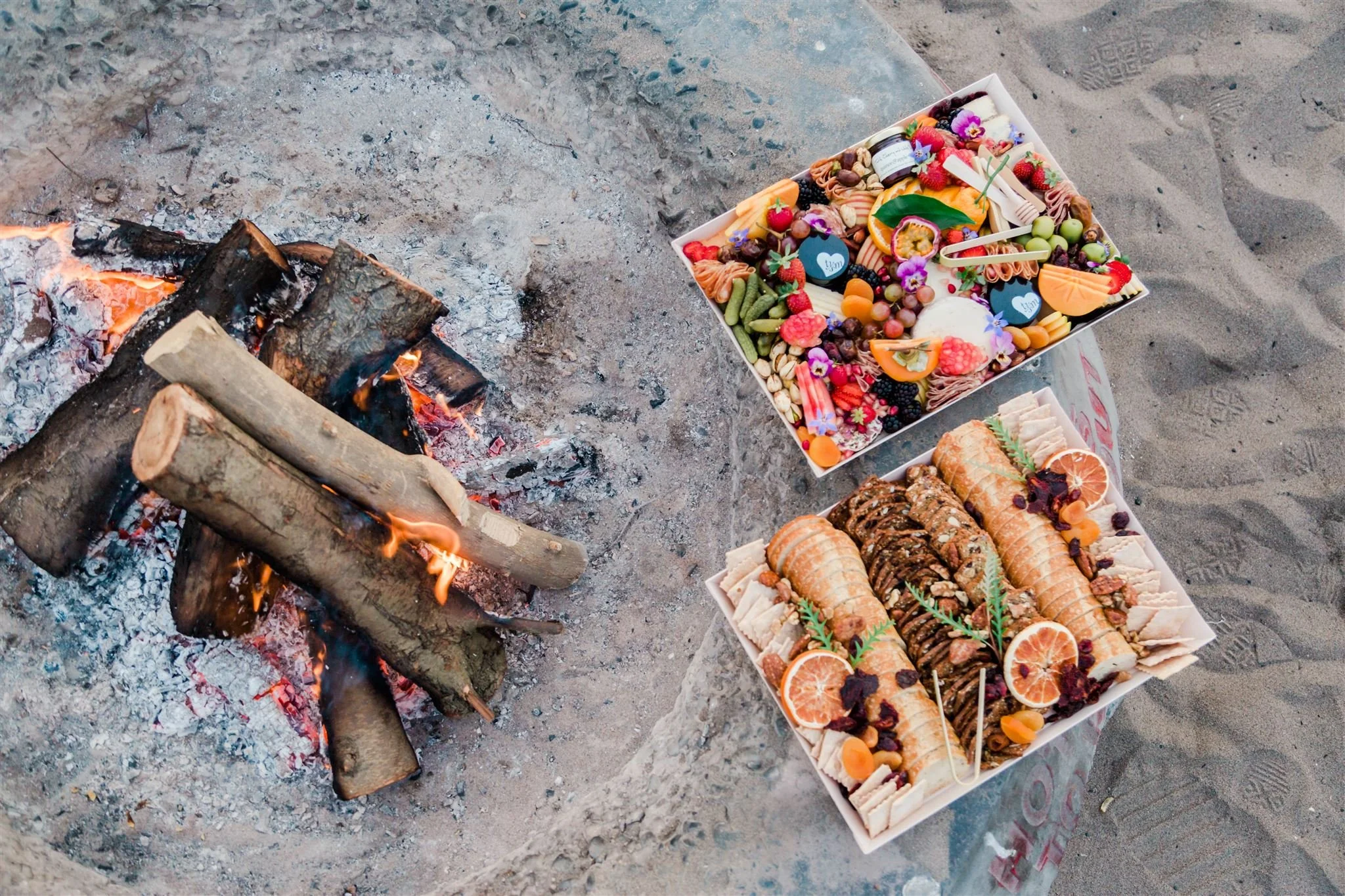 Charcuterie tray with meat, fruit, pickles and bread at a beach bonfire
