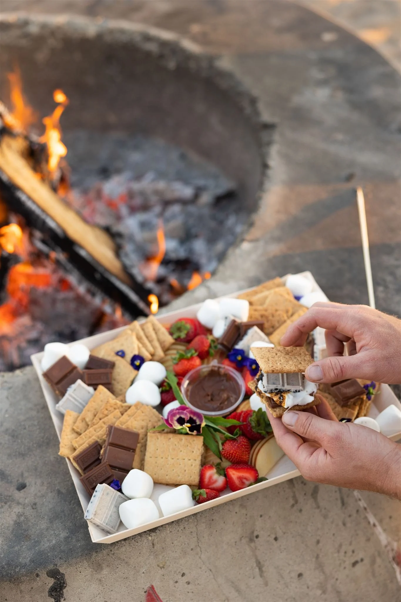 Smores tray with chocolate marshmallows strawberries at beach bonfire