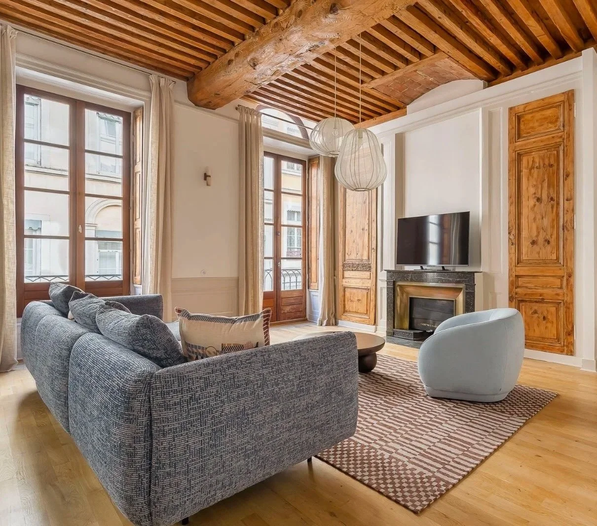 Bespoke linen curtains in a historic French living room with exposed wooden beams