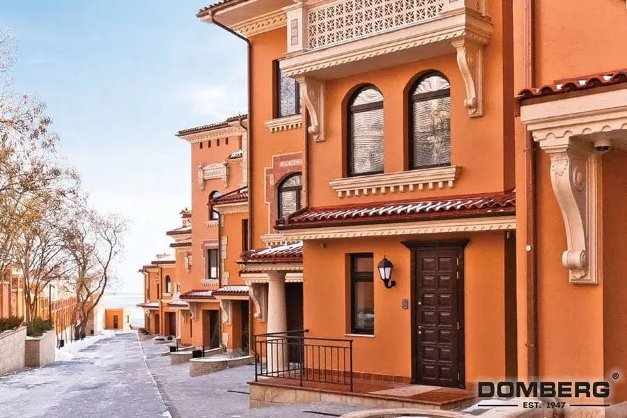 A row of Mediterranean-style orange stucco houses with red tile roofs and decorative white trim, along a snow-covered street