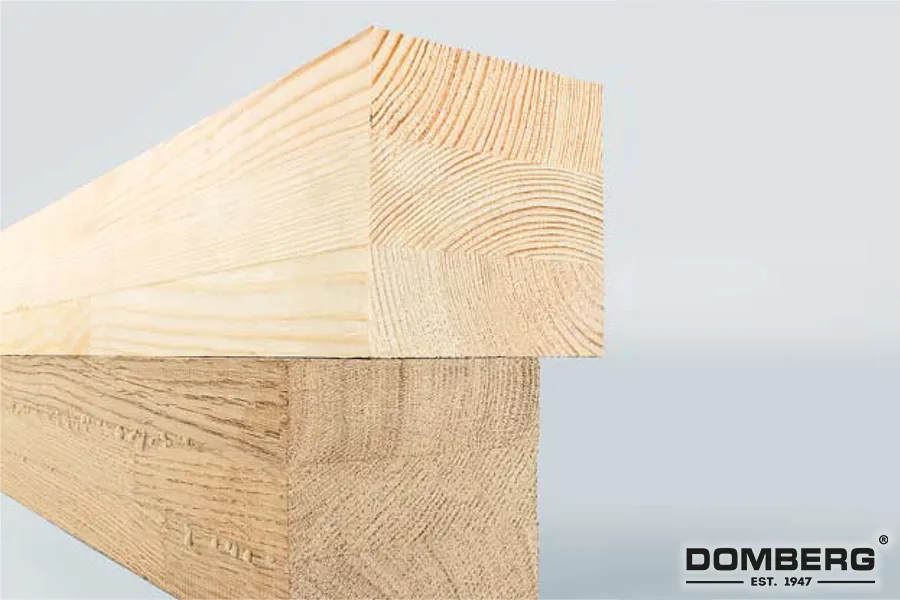 Close-up of stacked wooden beams showing their grain and texture against a light background, with the brand name DOMBERG and establishment year 1947 in the lower right corner.