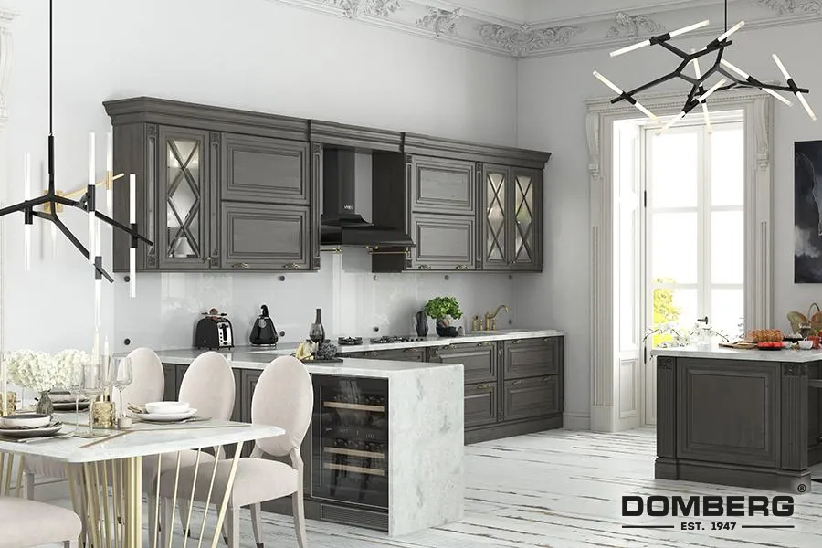 Modern kitchen with gray cabinets, white marble countertops, and a dining area with a white table and upholstered chairs. Two contemporary black and gold chandeliers hang from the ceiling. Large window letting in natural light.