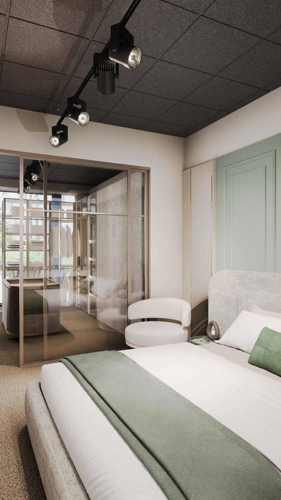Modern hotel room with a bed, green and white bedding, a white chair, and a glass-enclosed workspace with a desk and hanging clothes, under black track lighting.