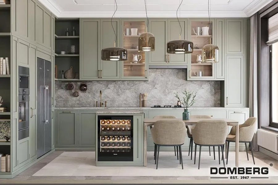 Kitchen with green cabinets, marble backsplash, beige dining chairs around a table, wine fridge, and pendant lighting, by Domburg.