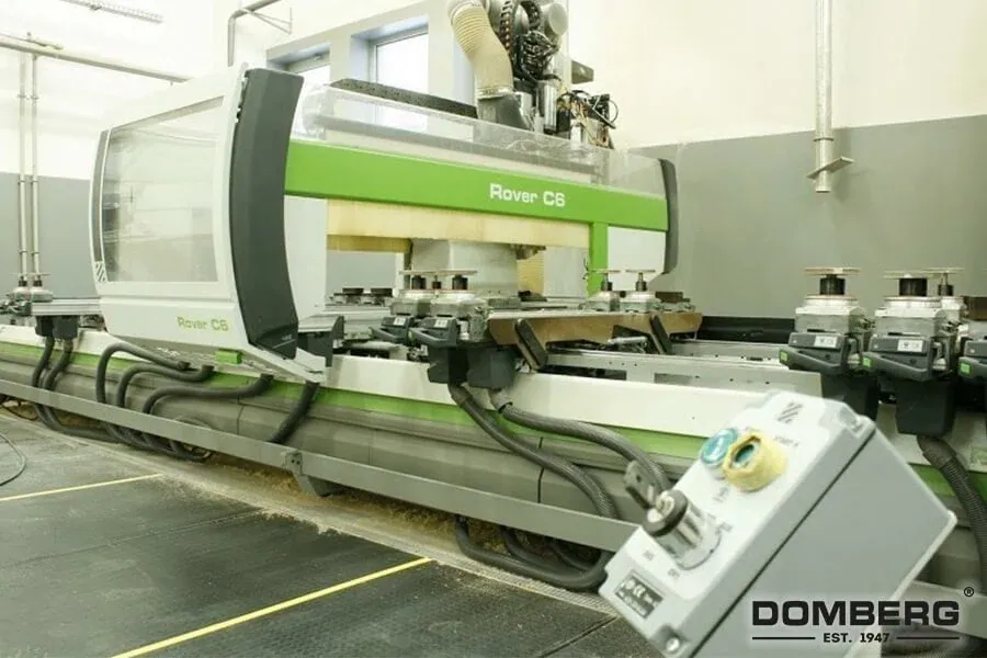 Large industrial CNC machine in a factory setting with control panel and cables connected