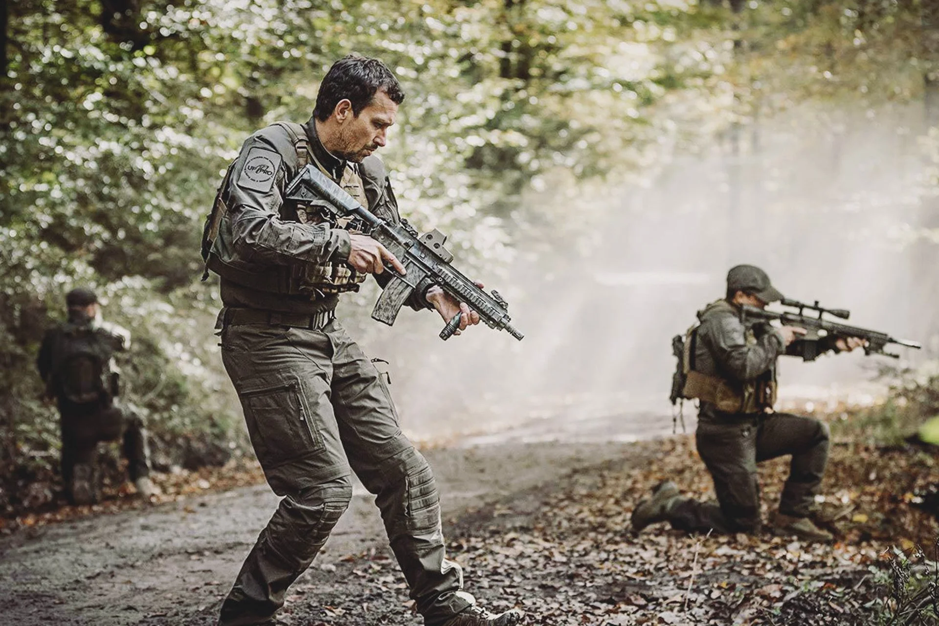 Einsatzkräfte mit taktischer Ausrüstung und Gewehren im Wald – UF PRO Bekleidung im taktischen Szenario.