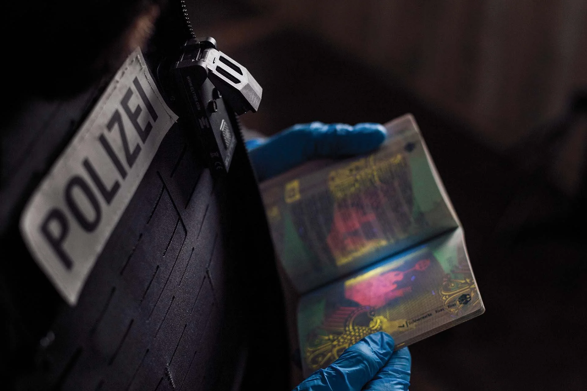 Polizeibeamtin mit Elyter Lampe überprüft Ausweis unter UV-Licht.