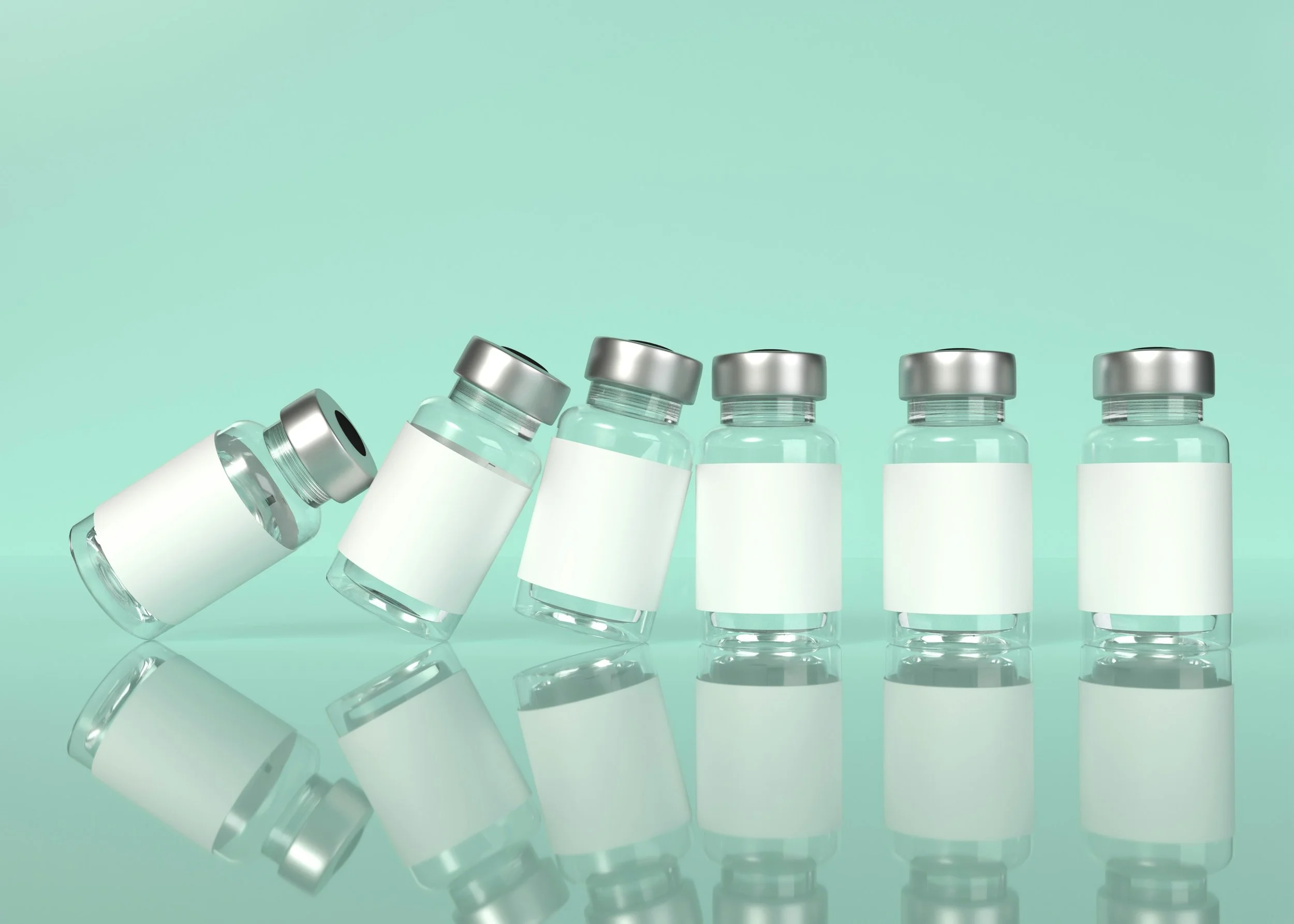 Sechs kleine, leere, transparente Vials mit silbernen Verschlüssen in einer Reihe auf einer reflektierenden Oberfläche, vor einem hellgrünen Hintergrund.