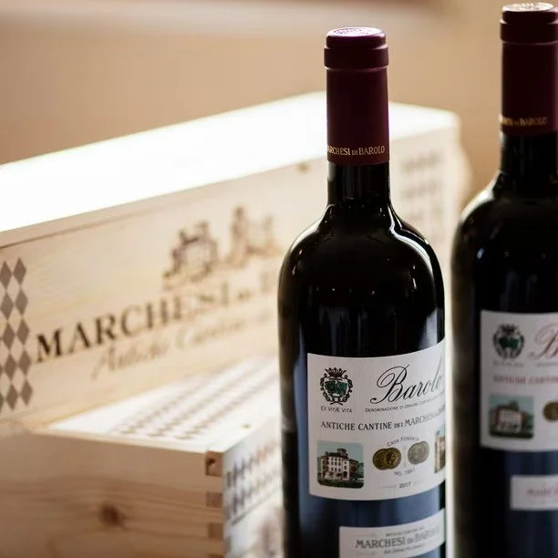 Two bottles of red wine on a table with a wooden box in the background.
