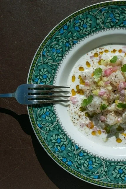 Assiette décorée avec un plat de nourriture, garnie de herbes, de sauce et d'ingrédients frais, accompagnée d'une fourchette sur une surface sombre.