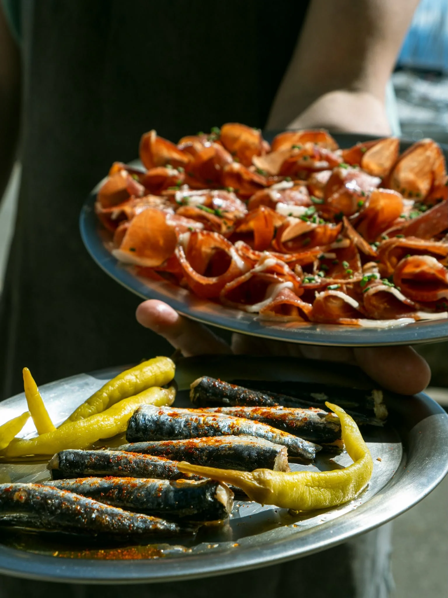 Assiette de poissons grillés accompagnés de poivrons jaunes. Personne tenant la plat