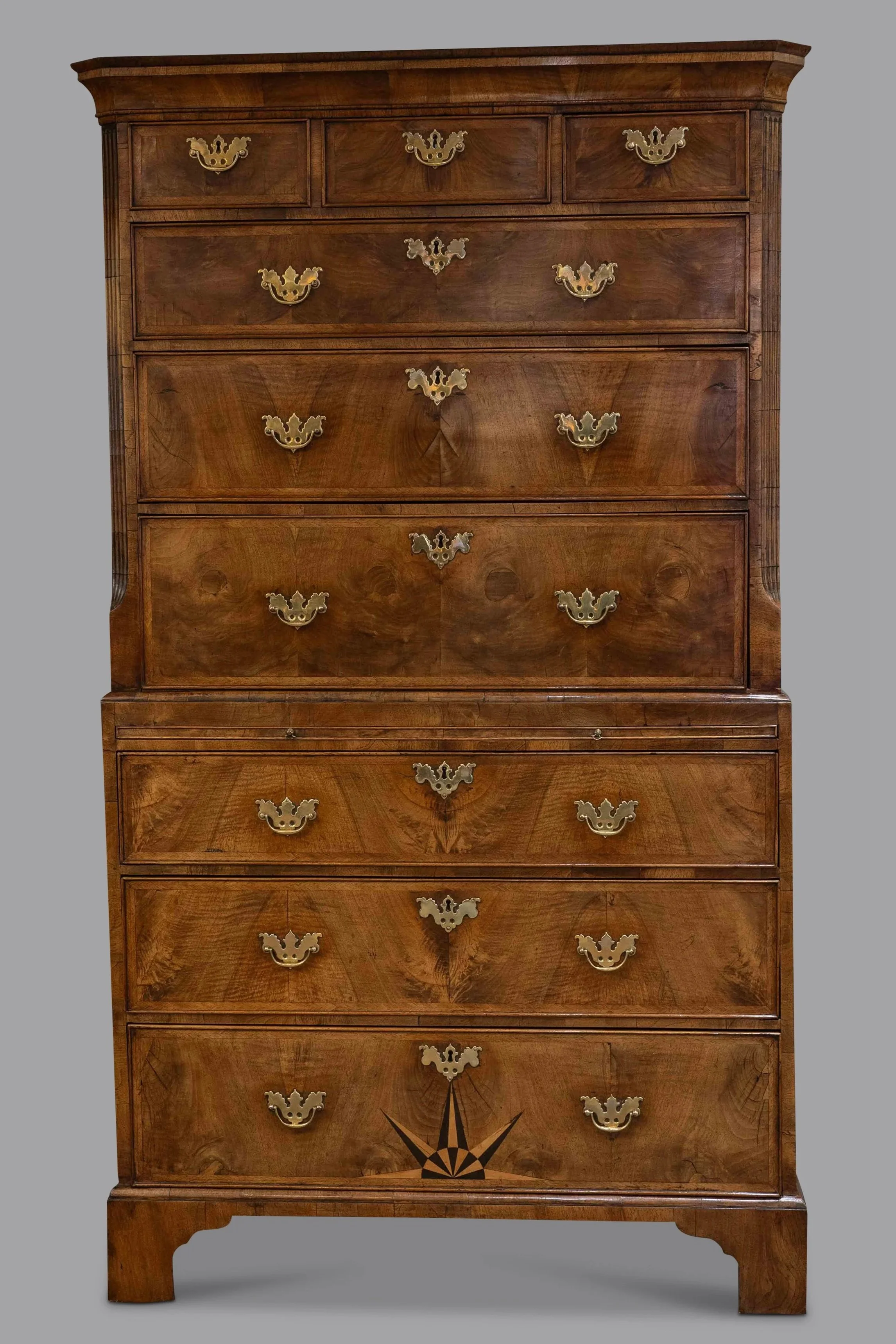 A tall wooden dresser with multiple drawers featuring ornate brass handles, decorative wood inlay, and a dark finish.