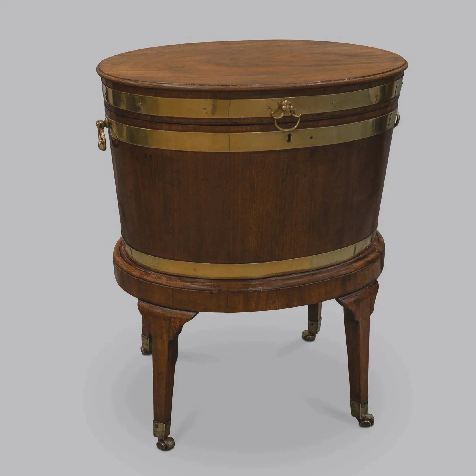 Antique wooden side table with brass accents and casters, on a plain grey background.