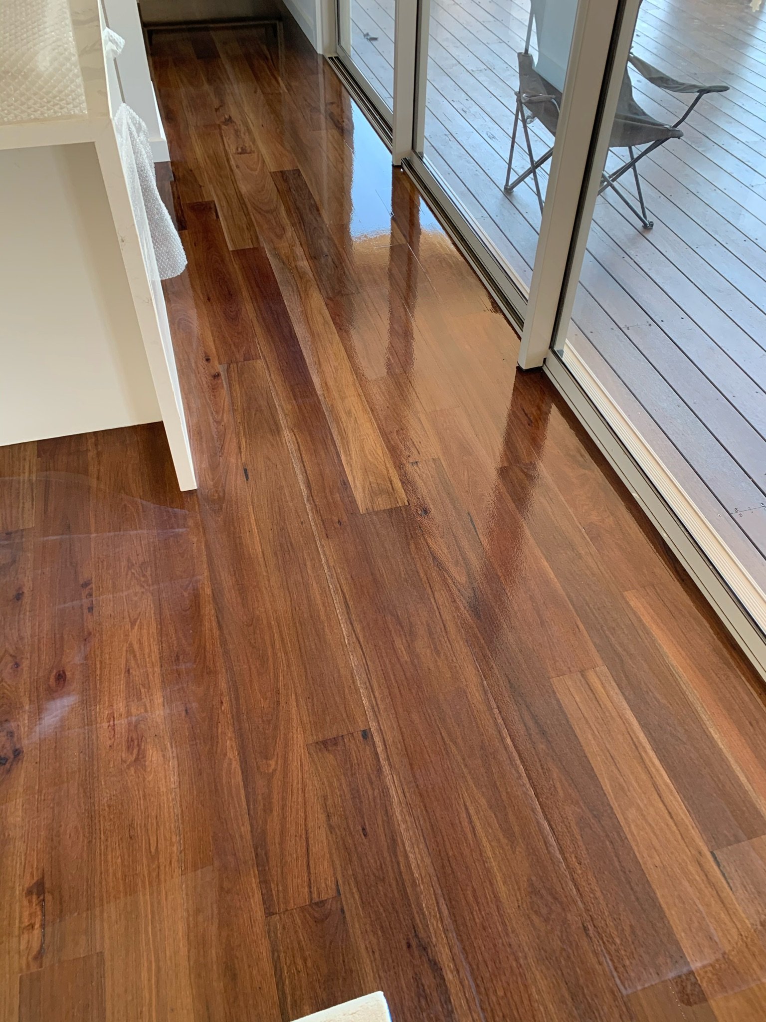 Shiny hardwood floor near glass sliding door with a small outdoor balcony visible.