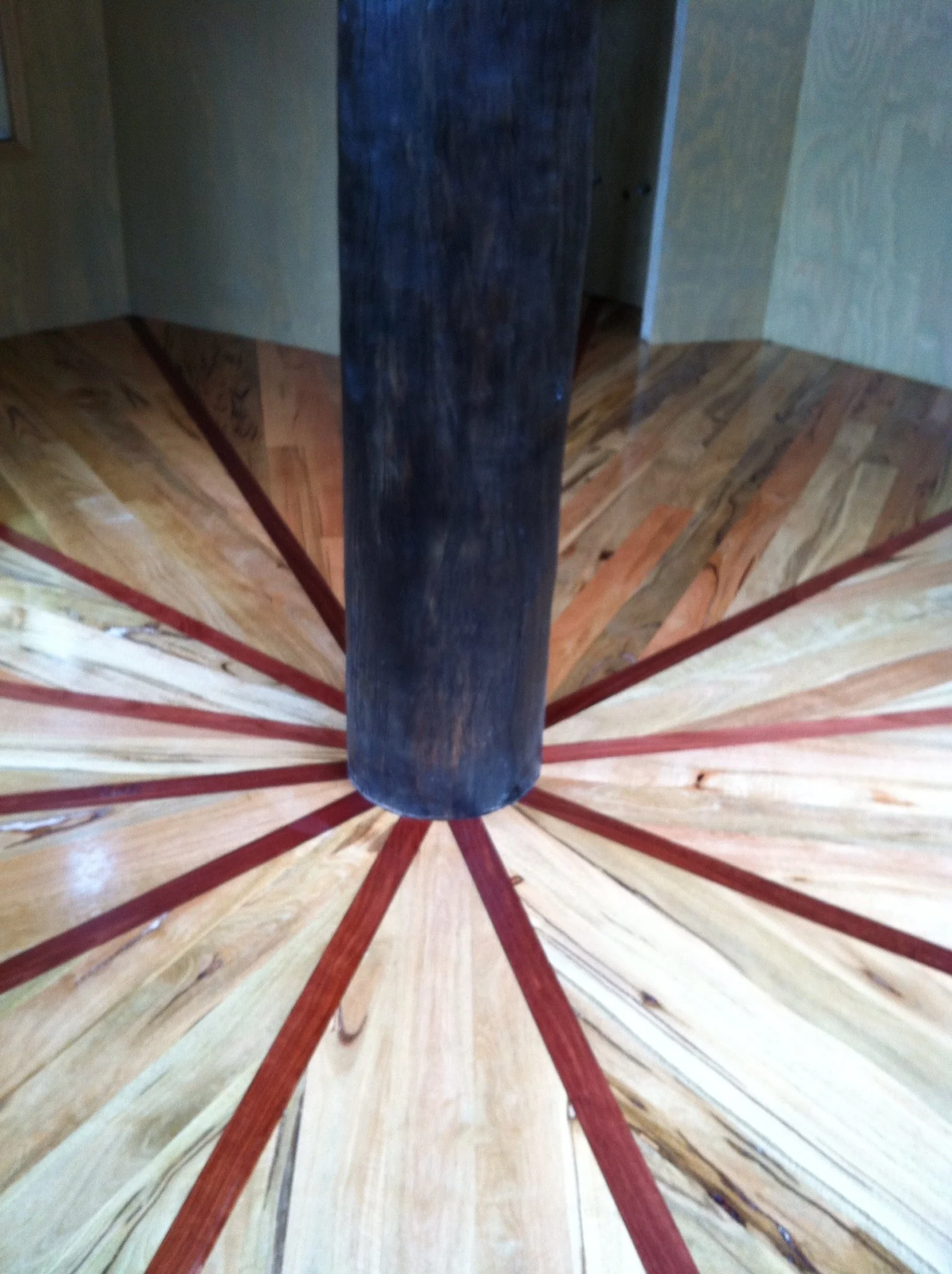 Close-up view of a wooden spiral staircase with a dark central support column at the center.