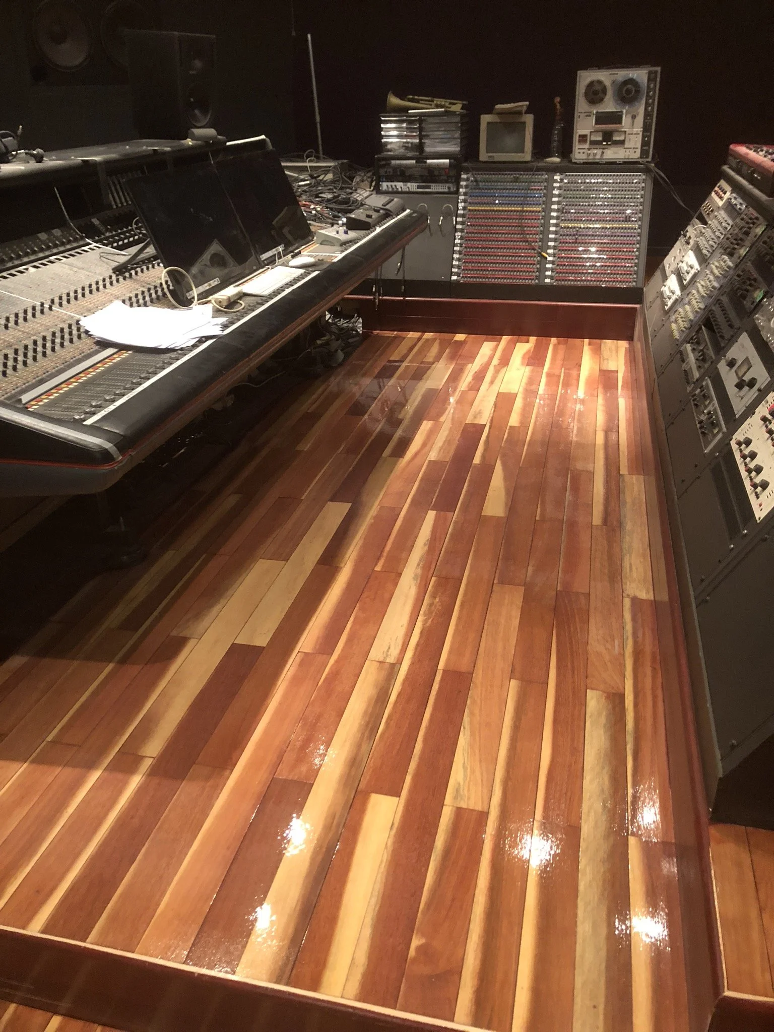 Recording studio with polished wooden floor, mixing console, and audio equipment.
