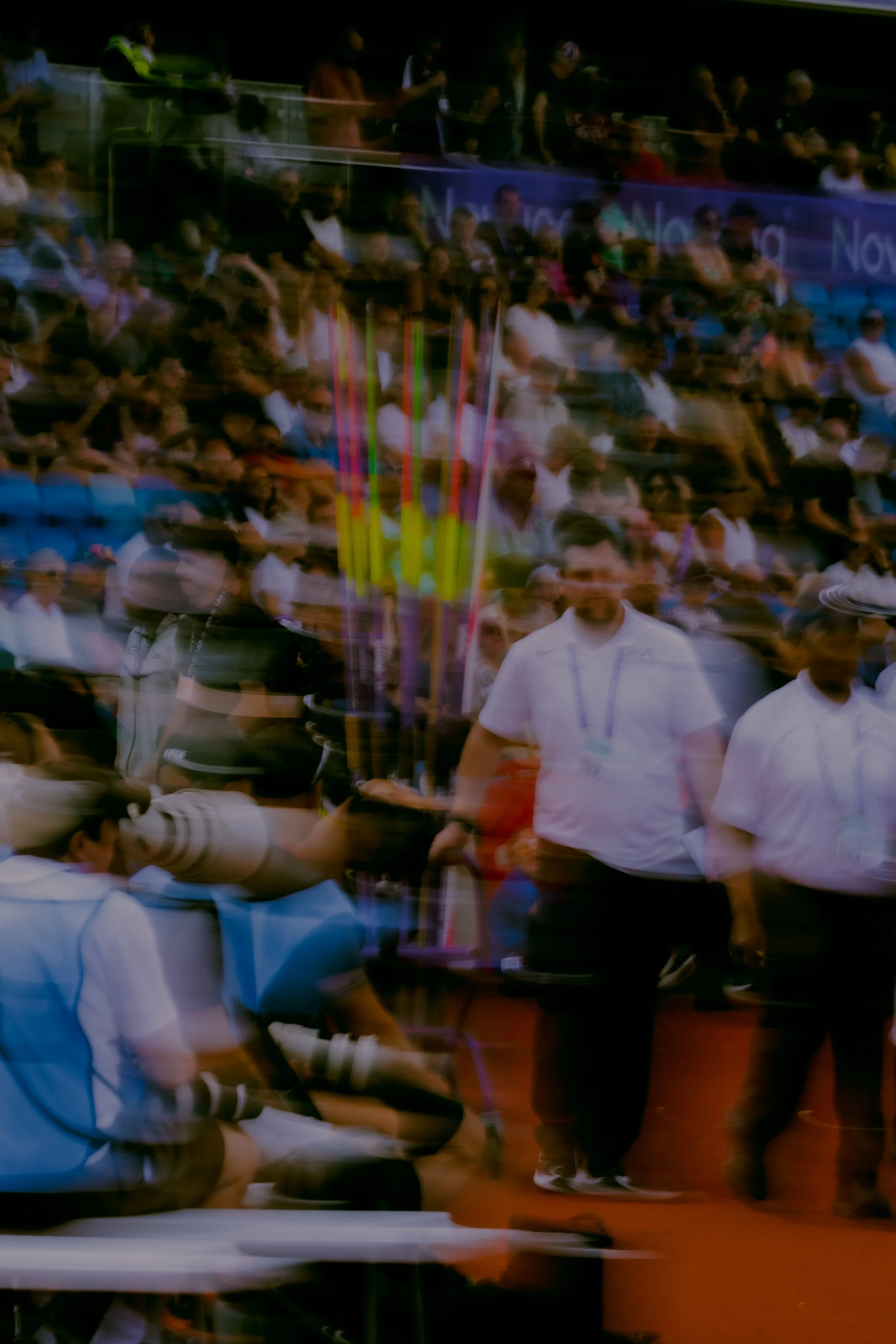 A photo of a crowded indoor event with people sitting and standing, with a colorful abstract design overlay.