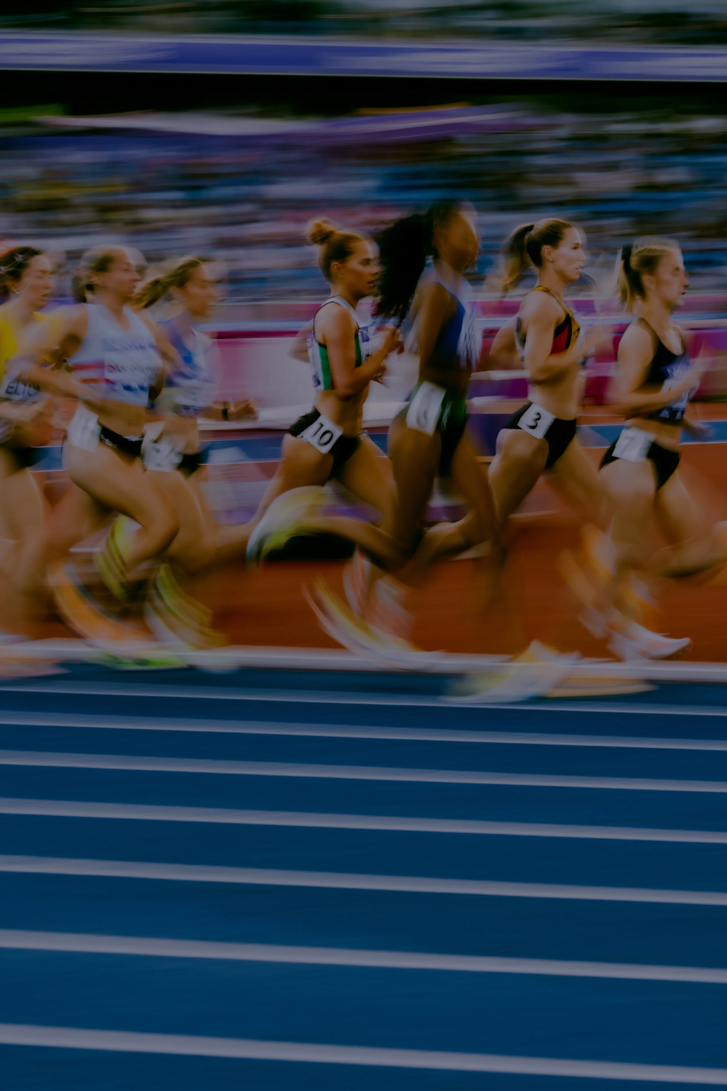 Track athletes running in a race, captured with motion blur to show speed.
