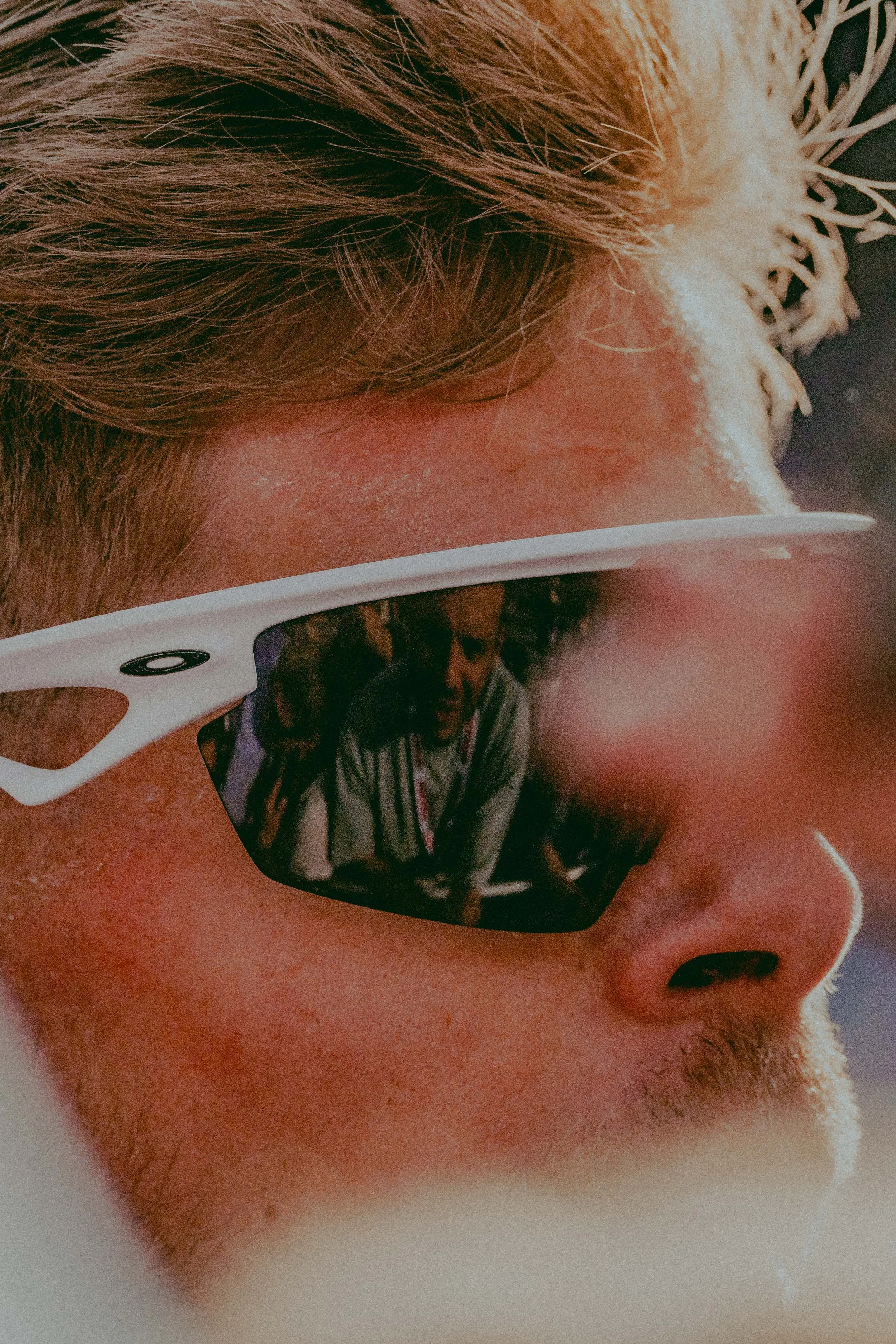 Close-up of a person's face wearing black sunglasses, showing part of their hair, nose, and cheek.