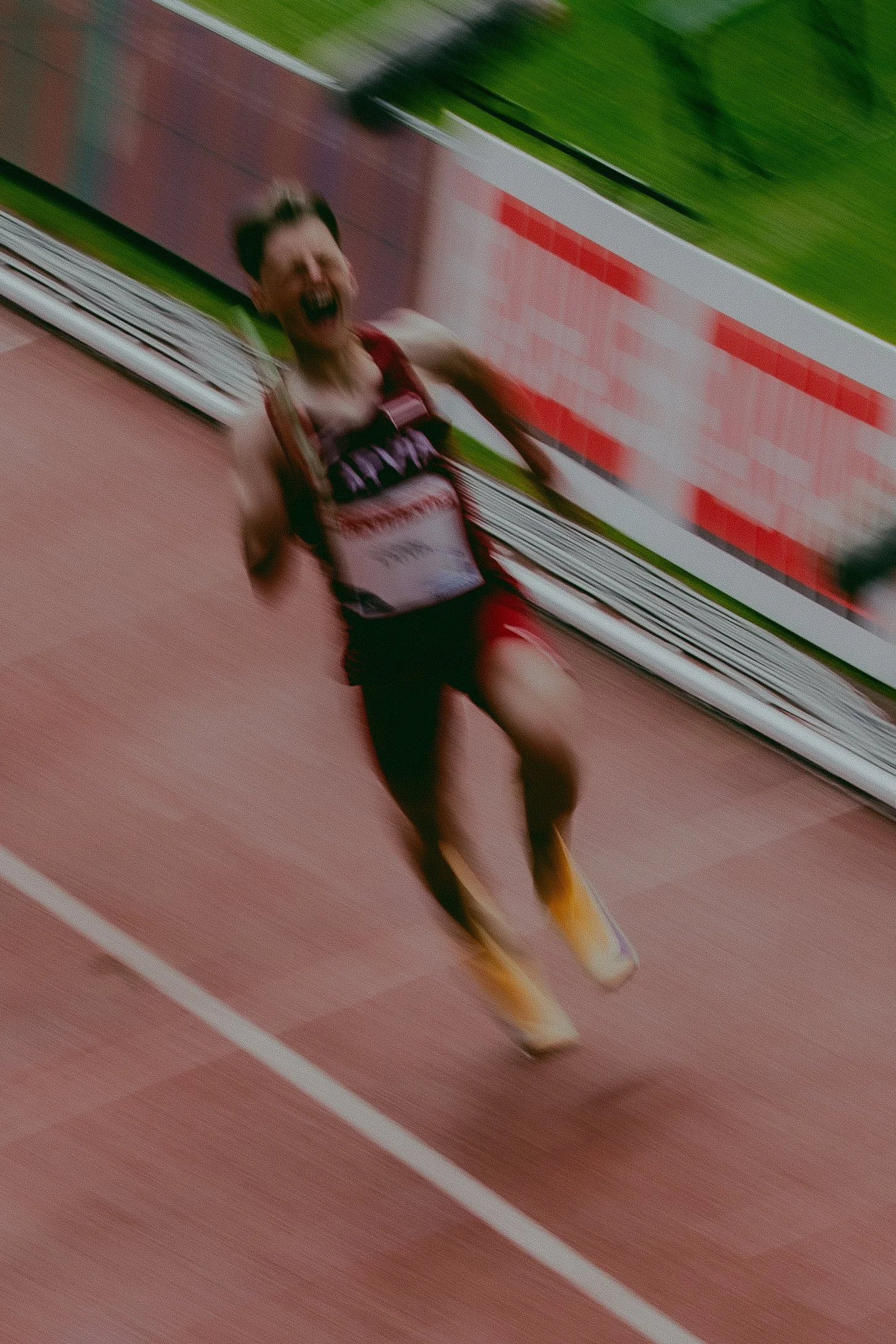 A runner celebrating after crossing the finish line at a track event, with a blurred background indicating motion.