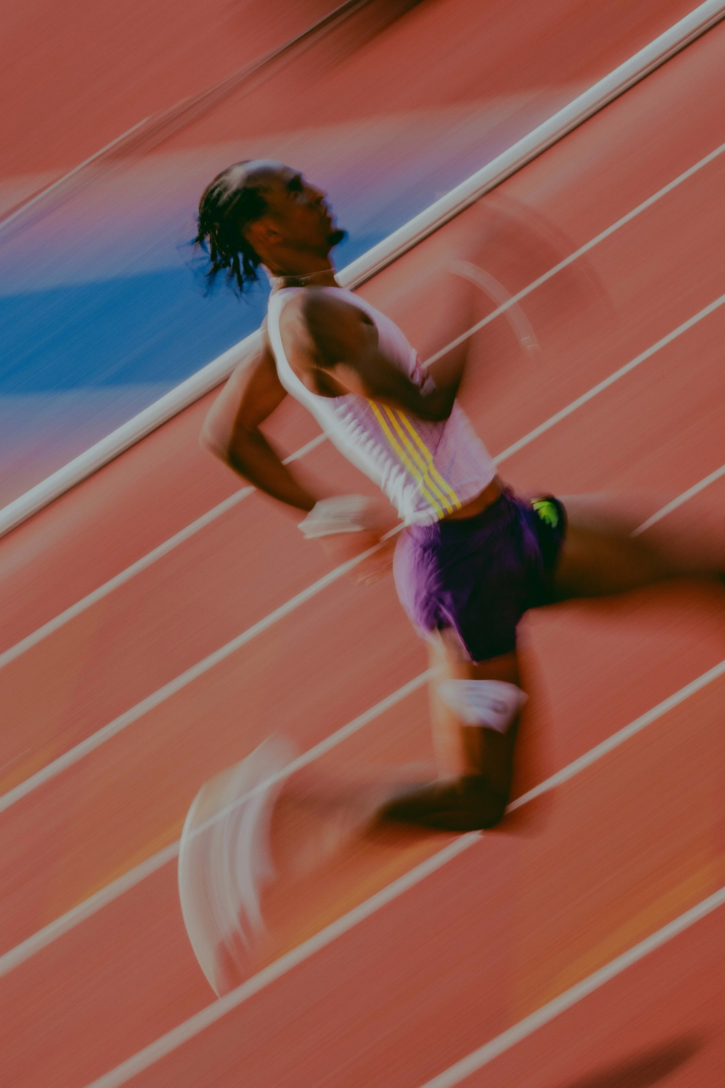 Male athlete running on a red track during a race.