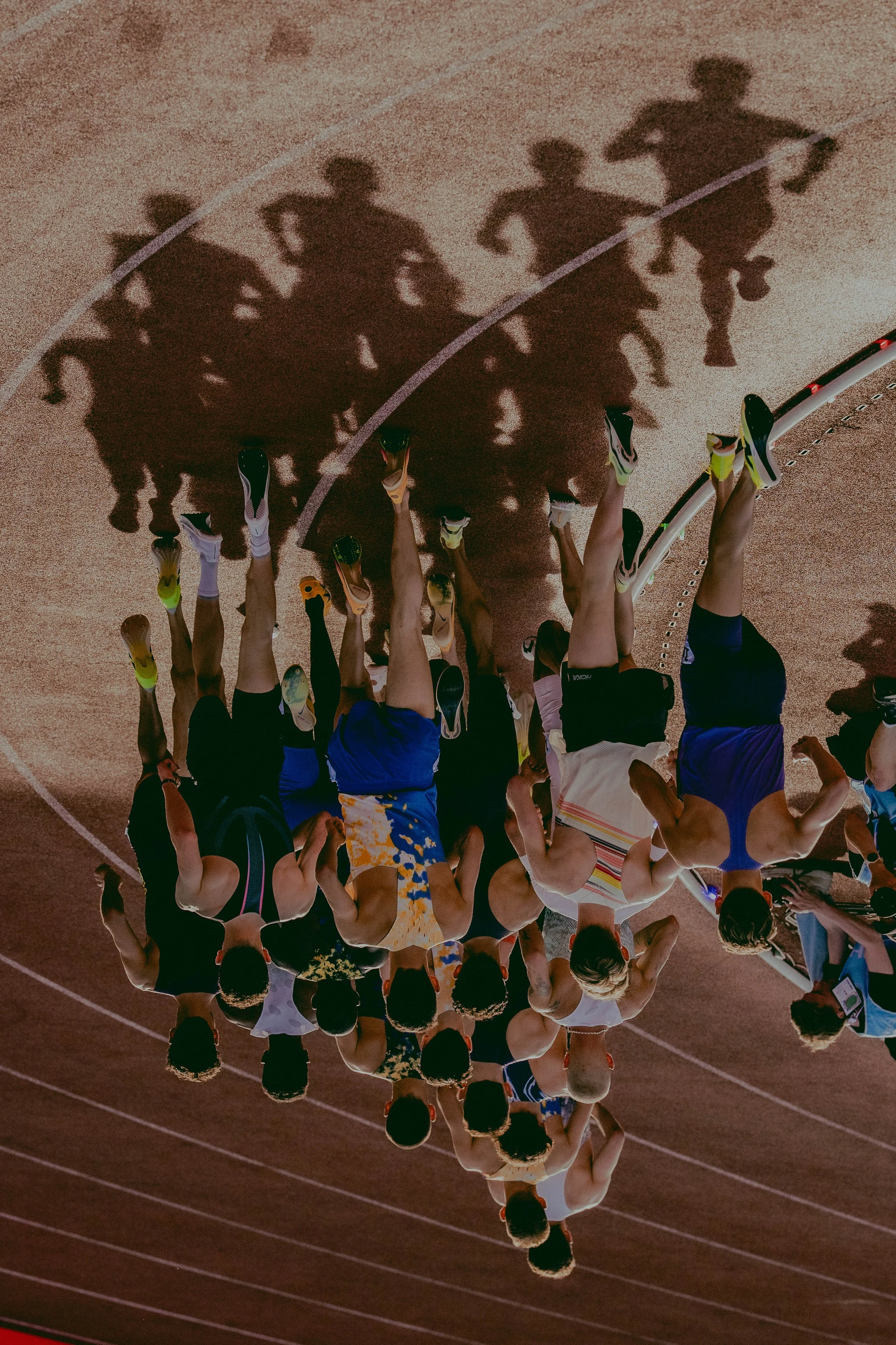 View of athletes running on a track, shadow cast on the ground
