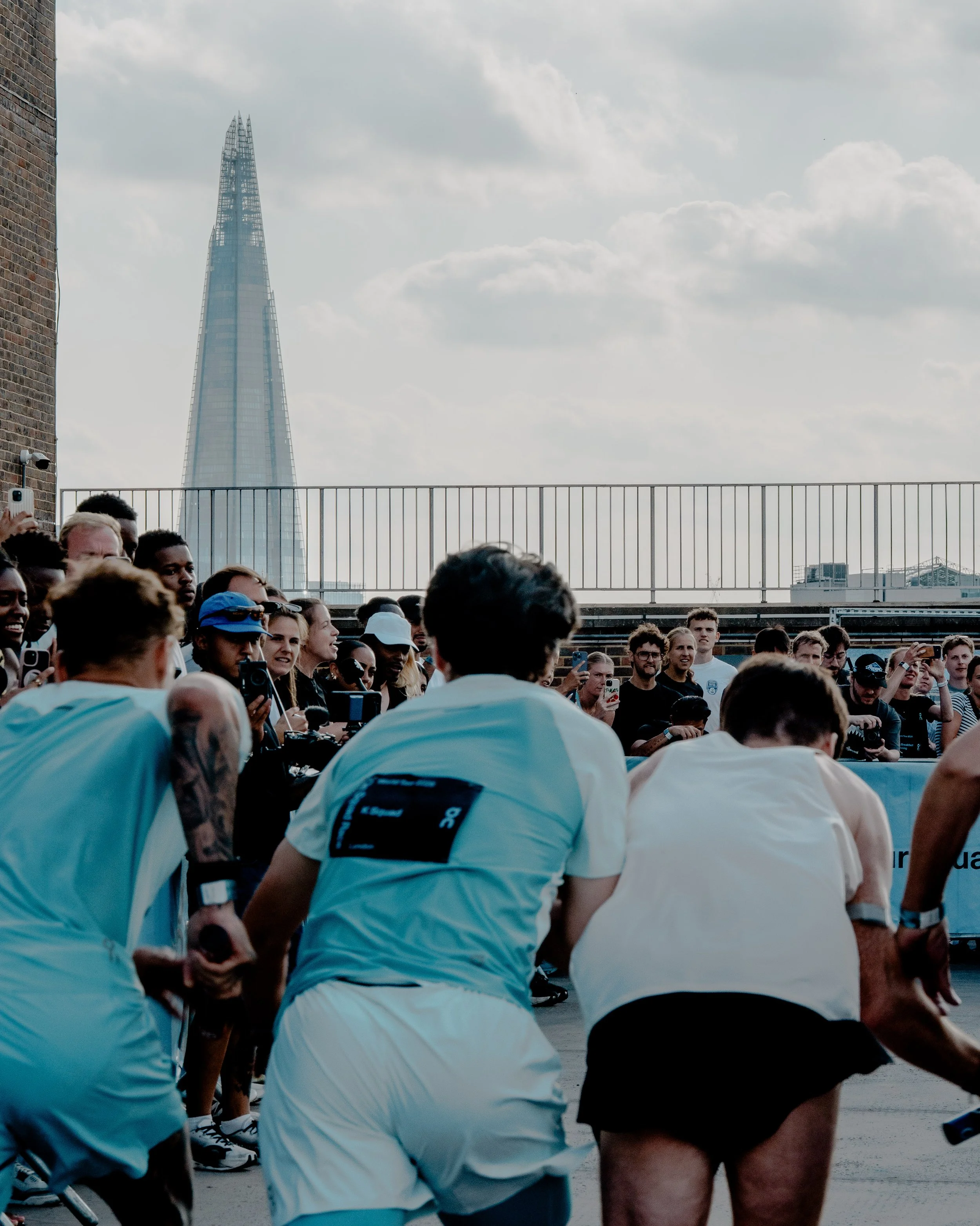 Crowd of people running outdoors in an urban setting with the city skyline, including The Shard, visible in the background.
