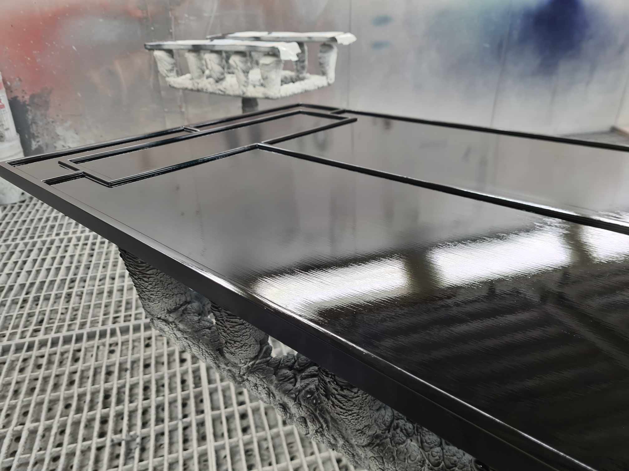 A glossy black stovetop with metal grates on a countertop in a painting or spray booth.