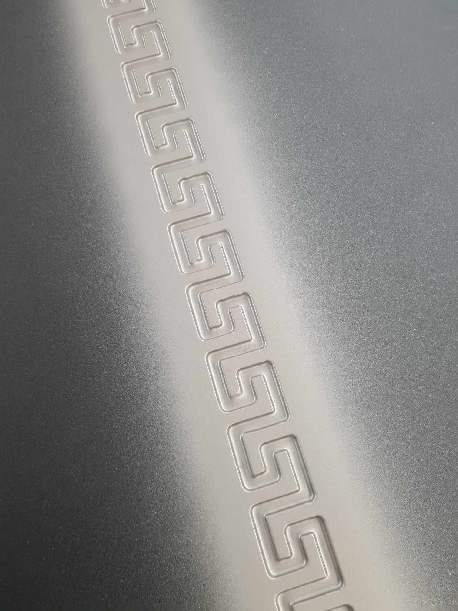 Close-up of a metallic surface with an embossed geometric pattern.