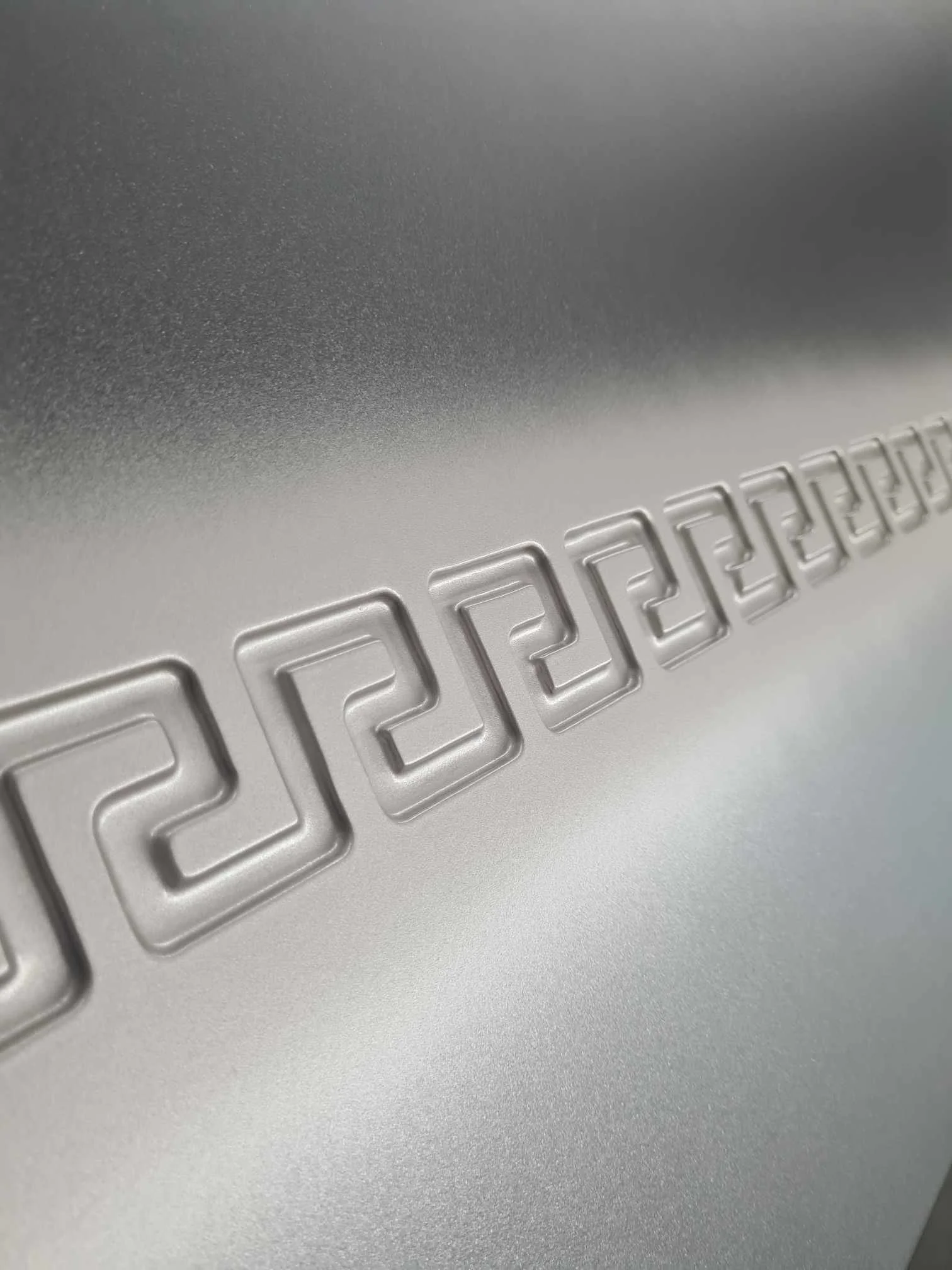 Close-up of a metallic surface with a textured pattern, embossed with the word 'Porsche' in stylized letters.