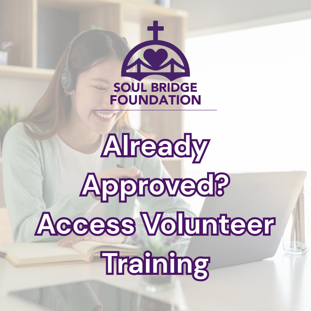 A woman with headphones sitting at a desk, smiling and looking at her laptop, with a notebook open in front of her, in a well-lit room with wooden shelves in the background.
