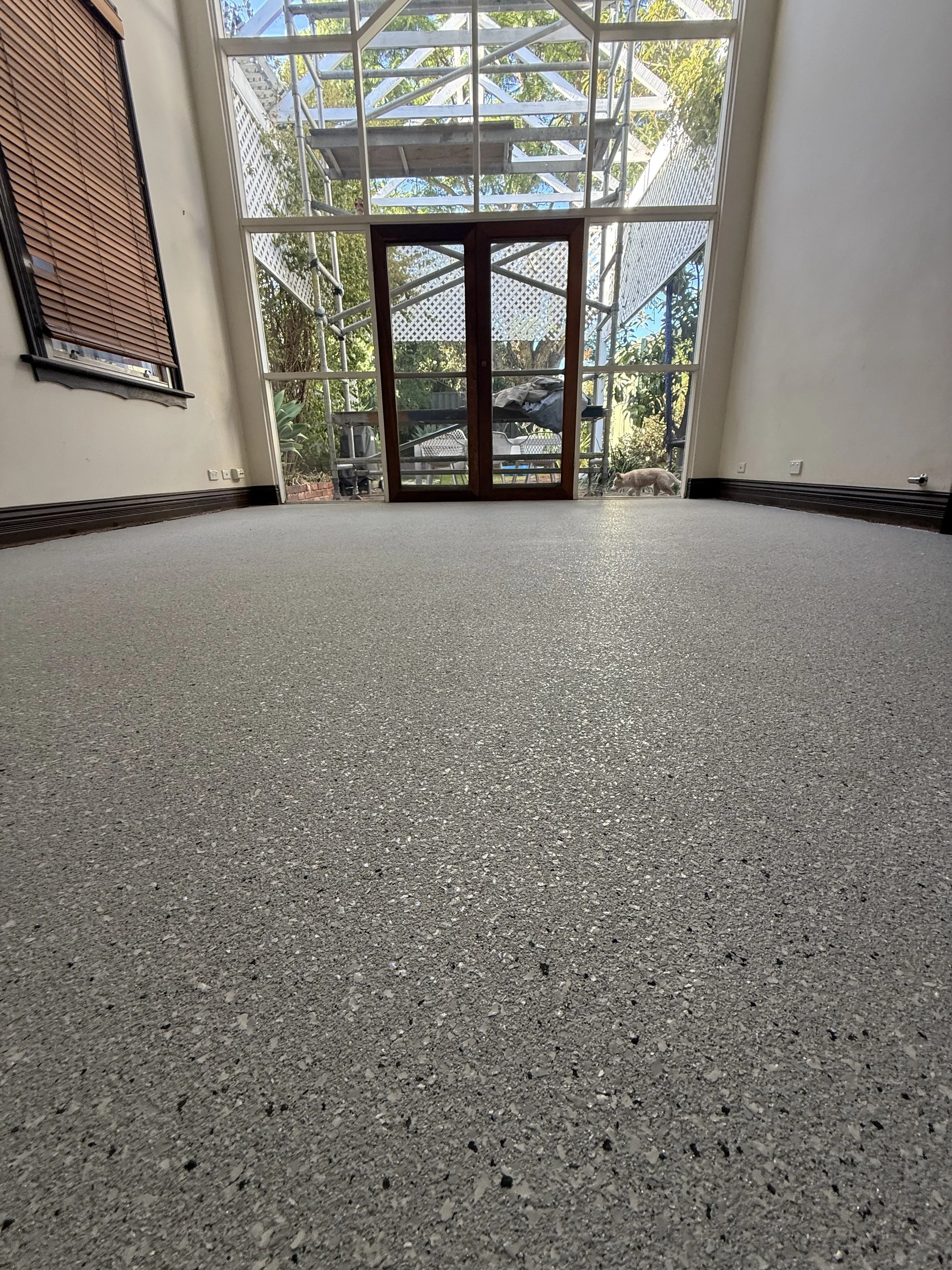 Residential interior floor finished with a full flake epoxy coating installed over existing tiles, creating a seamless, durable, and low-maintenance surface. This flake flooring system gives the space a clean modern look while covering old tiled floo
