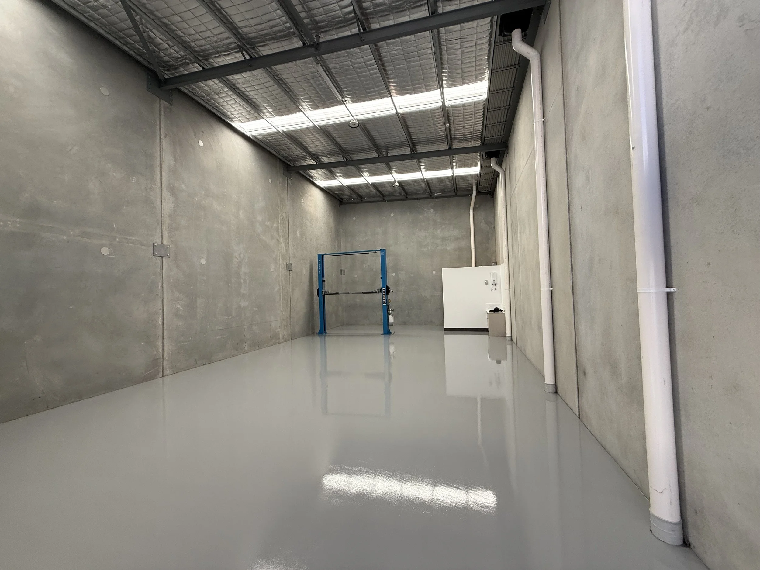 Premium warehouse floor finished with a grey polyaspartic coating, applied over professionally prepared concrete for a seamless, durable, and high-gloss commercial surface. This industrial flooring system is ideal for warehouses, storage units, and c