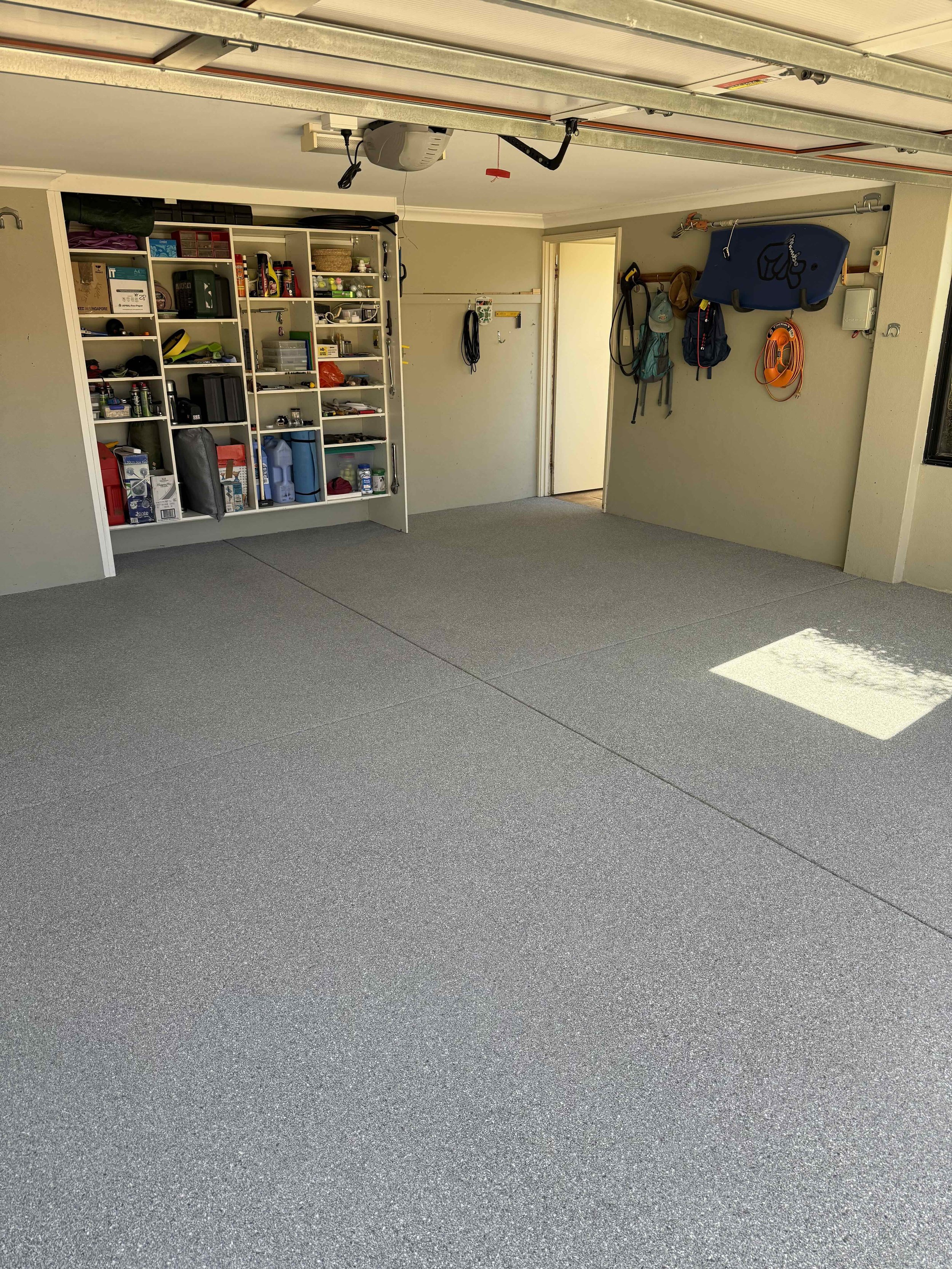 Epoxy flake garage with organized shelves, tools, and hooks on the wall.
