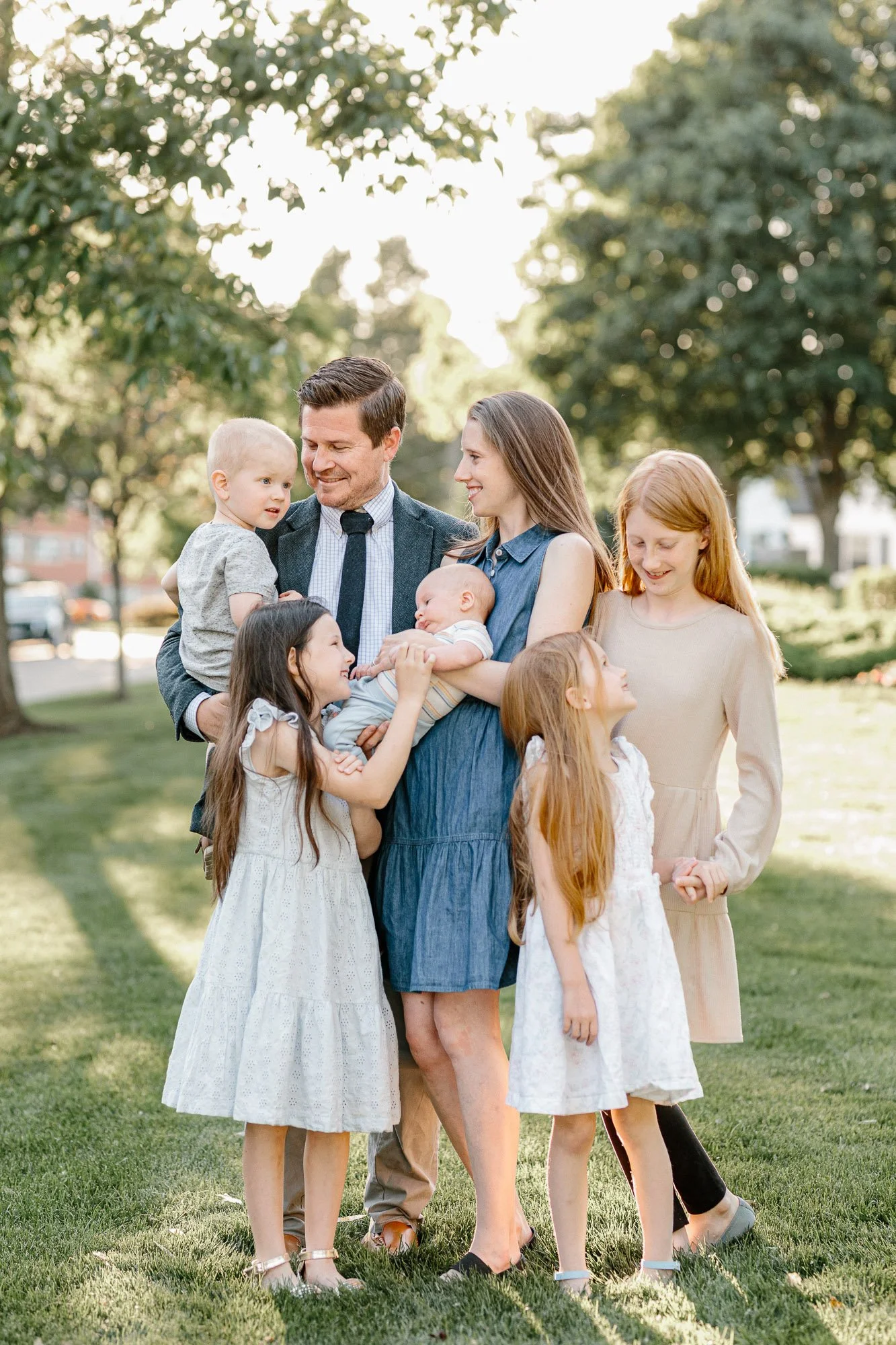 large family of 7 looking at and smiling at one another during a family session in downtown  Arlington Heights