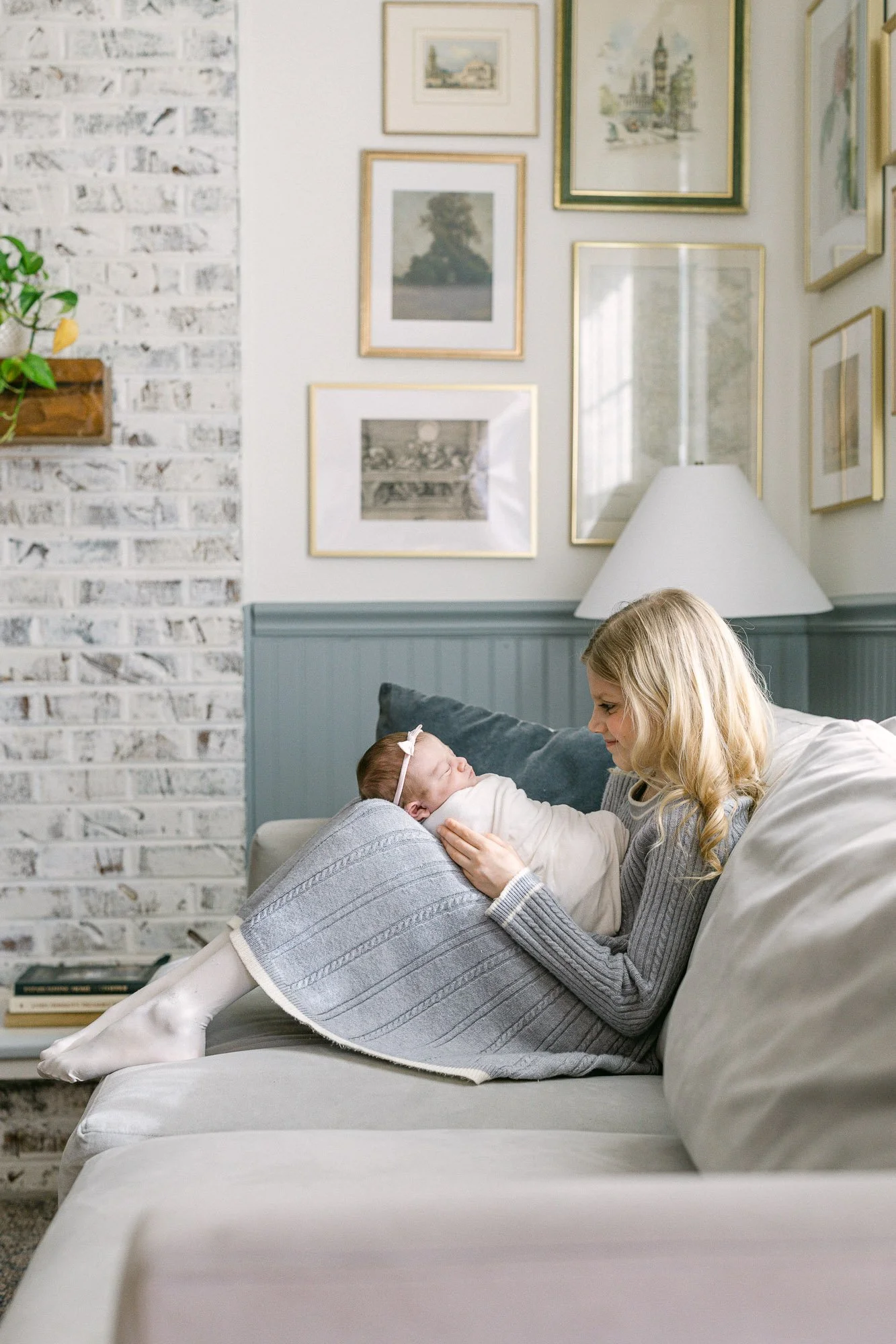 big sister holding her baby sister with a gallery of framed art in the background designed by Aberle Design Co.