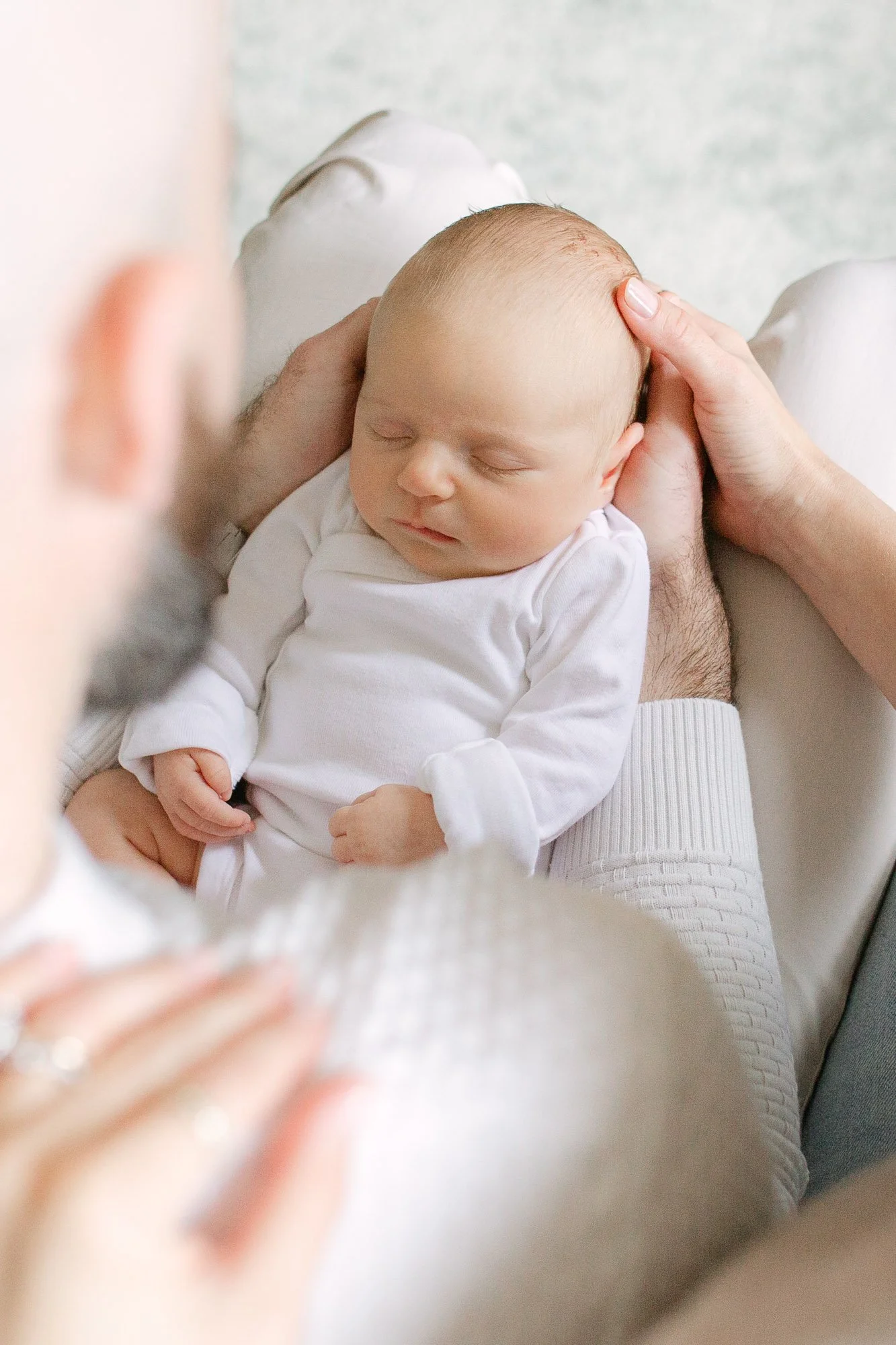 over the should view of a mom and dad holding their newborn baby during an in home newborn session in Chicago