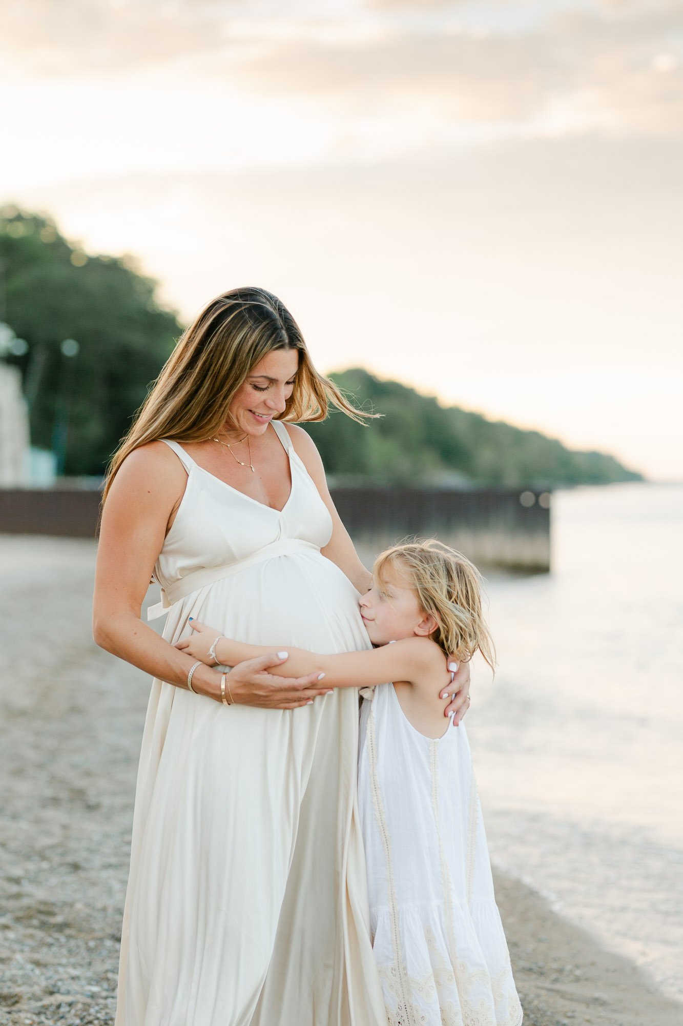 daughter hugging pregnant mom during Glencoe Beach maternity photo session