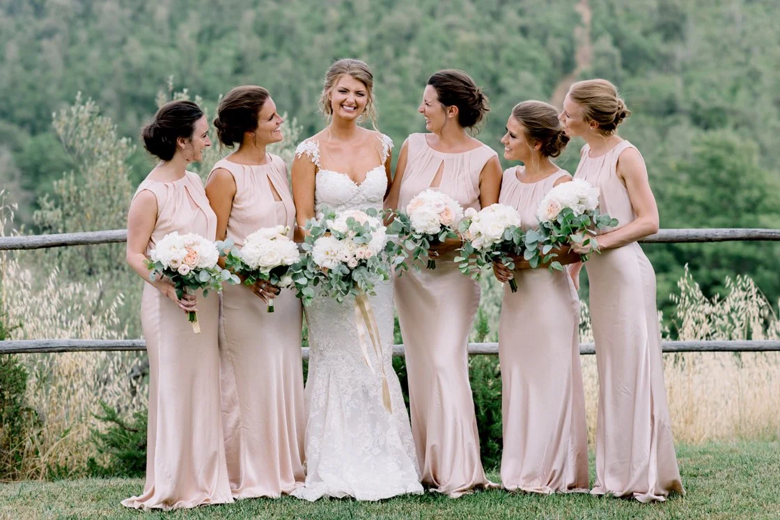 Bruid met haar bruidsmeisjes bij Conti di San Bonifacio in Toscane, allemaal met bloemenboeketten – een intiem moment tijdens een destination wedding, gepland door FunkyBird Weddings.
