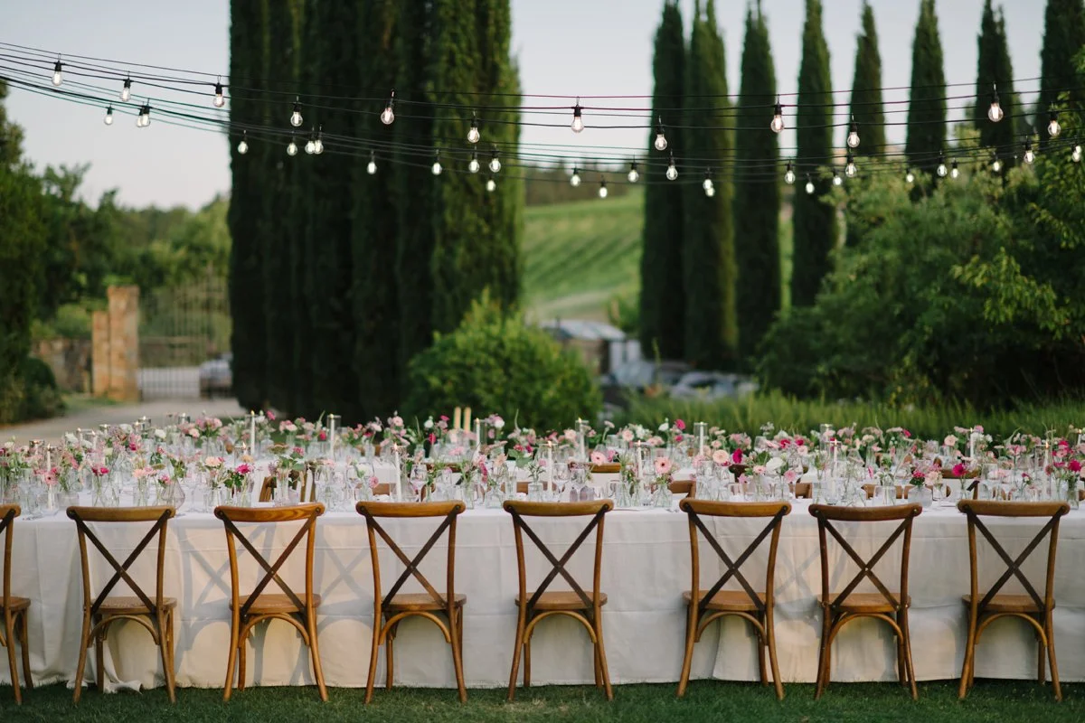 Adembenemende tafeldecoratie bij Borgo della Meliana, met lange Toscaanse cipressen op de achtergrond – elegante bruiloftsstyling in Italië met bloemen en sfeerdesign van FunkyBird.