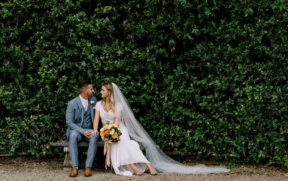 Bruidspaar zit samen op een bankje in de tuin van Villa Cora in Florence – een rustig en stijlvol moment tijdens hun elopement in Italië, gepland door FunkyBird Weddings.